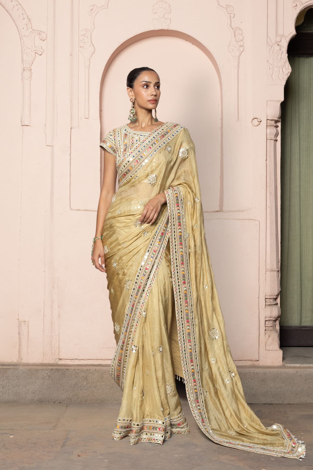 Gold saree with intricate mirror embroidery and sequin detailing, paired with a matching embroidered blouse.