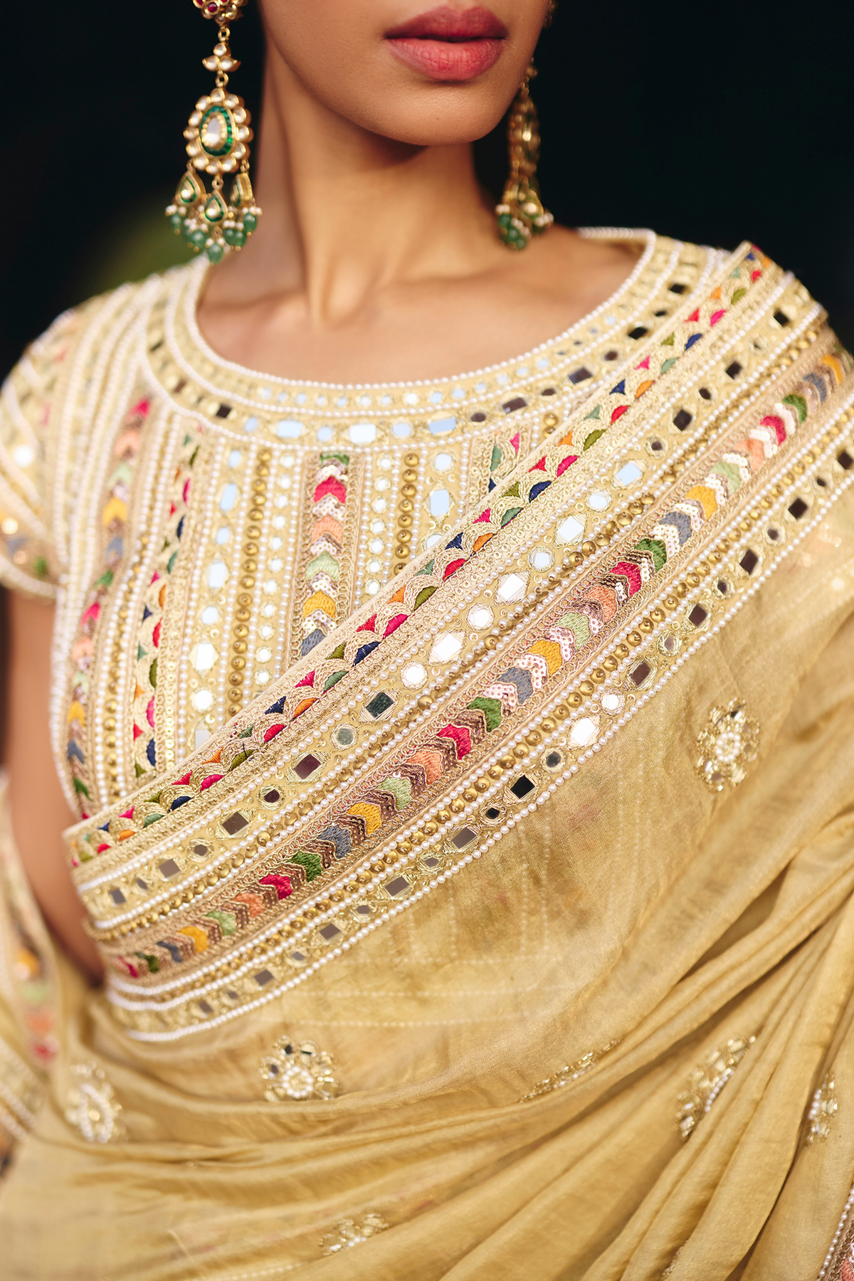 Gold saree with intricate mirror embroidery and sequin detailing, paired with a matching embroidered blouse.