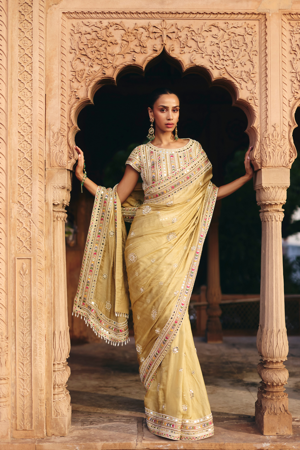 Gold saree with intricate mirror embroidery and sequin detailing, paired with a matching embroidered blouse.