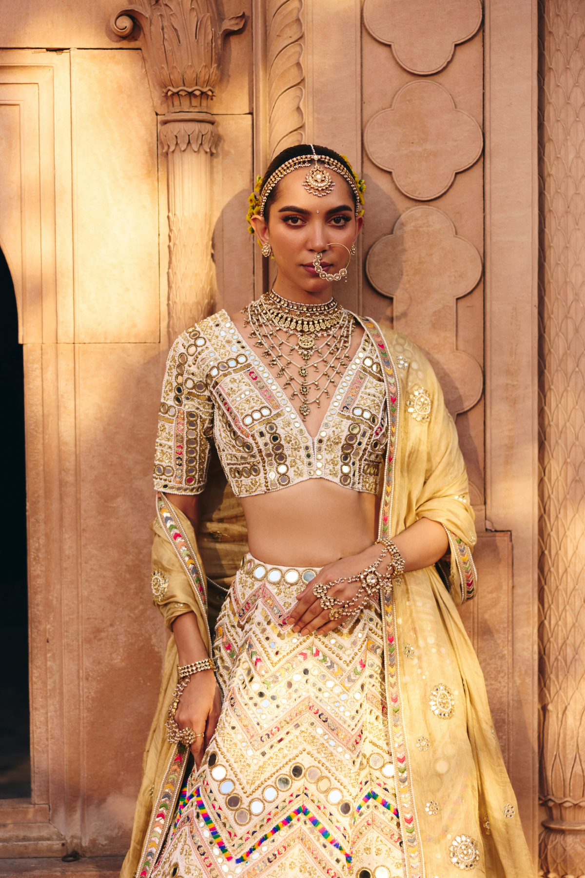 Ivory lehenga with intricate mirror embroidery, paired with a matching embroidered blouse and gold dupatta.