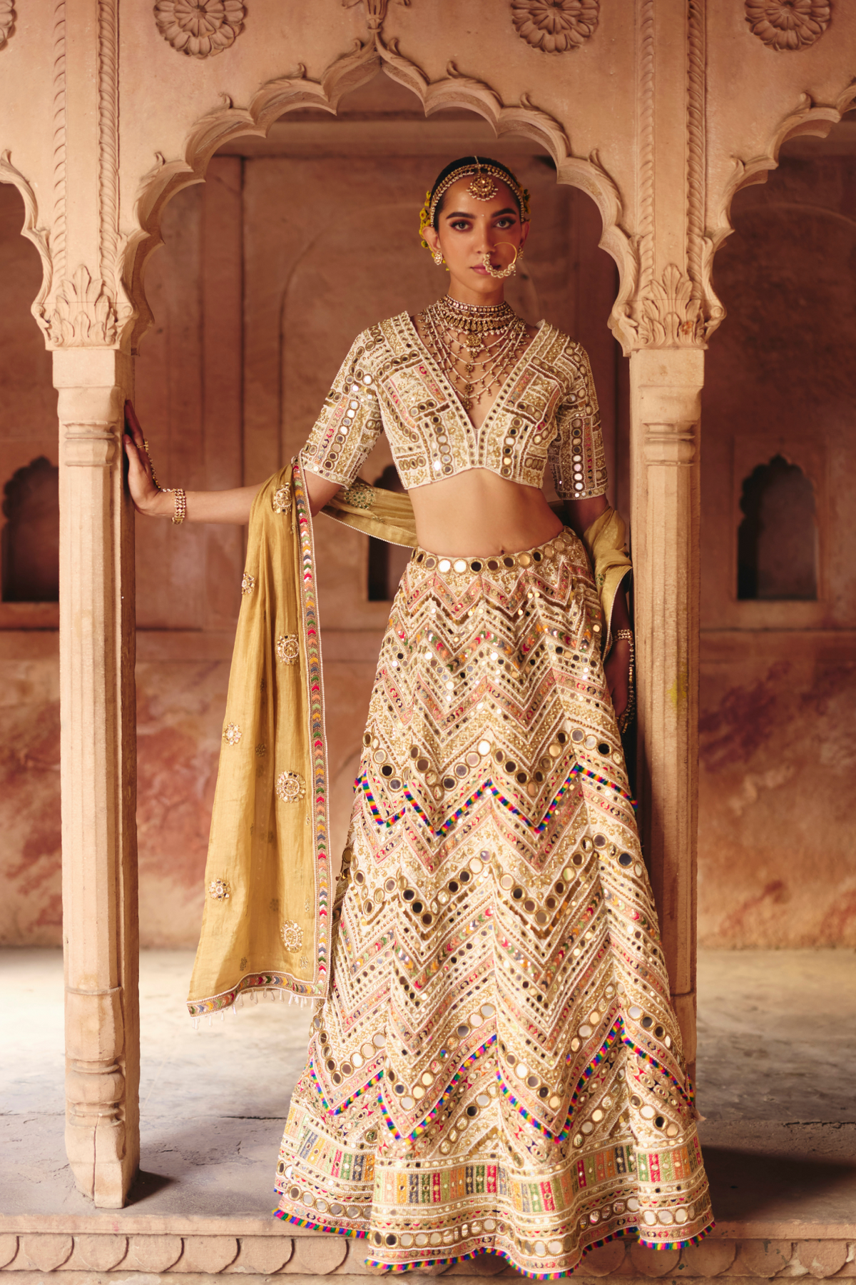 Ivory lehenga with intricate mirror embroidery, paired with a matching embroidered blouse and gold dupatta.