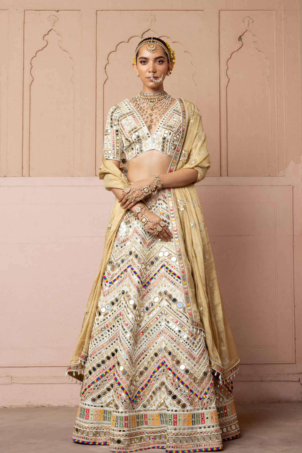 Ivory lehenga with intricate mirror embroidery, paired with a matching embroidered blouse and gold dupatta.