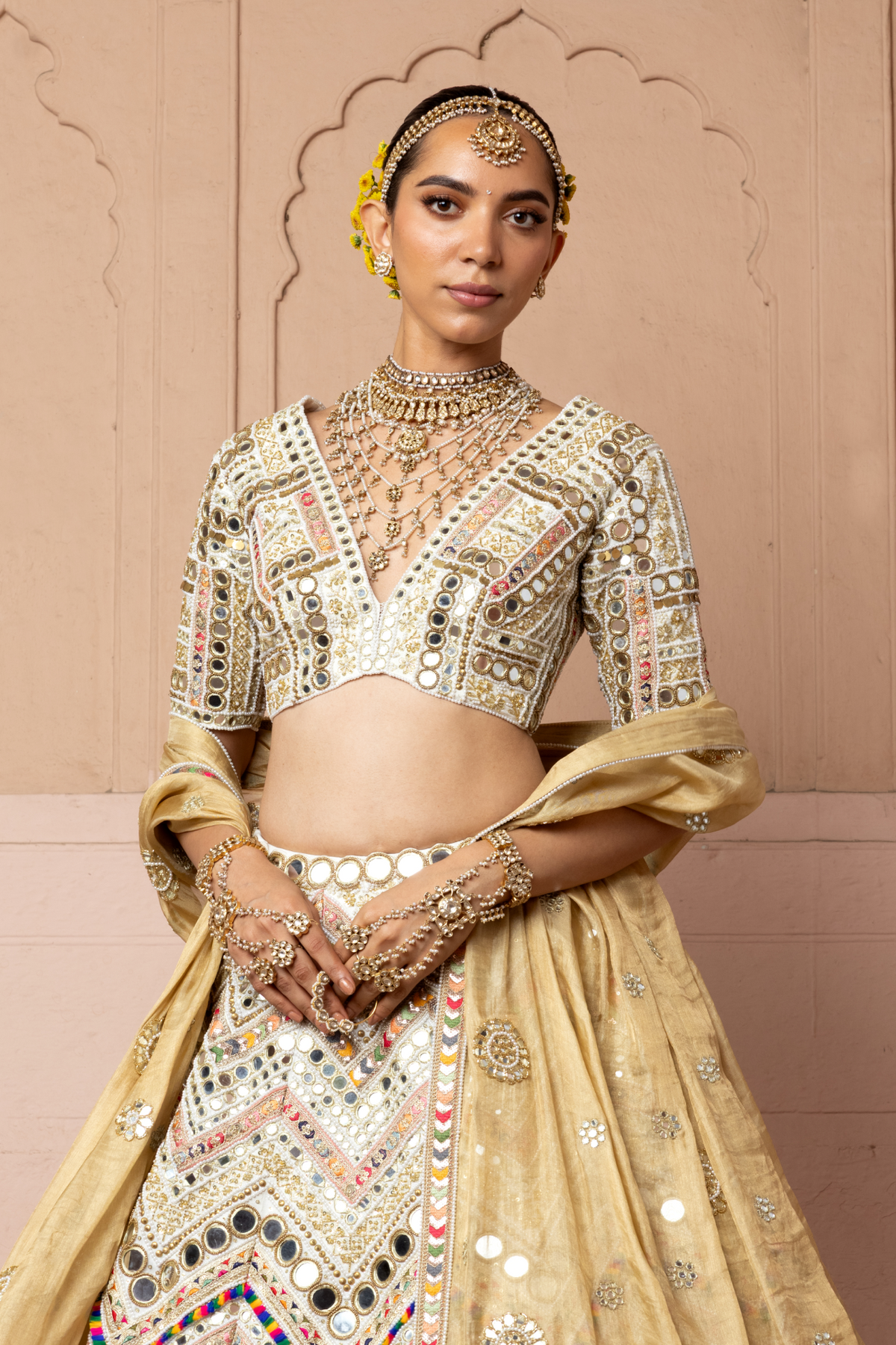 Ivory lehenga with intricate mirror embroidery, paired with a matching embroidered blouse and gold dupatta.