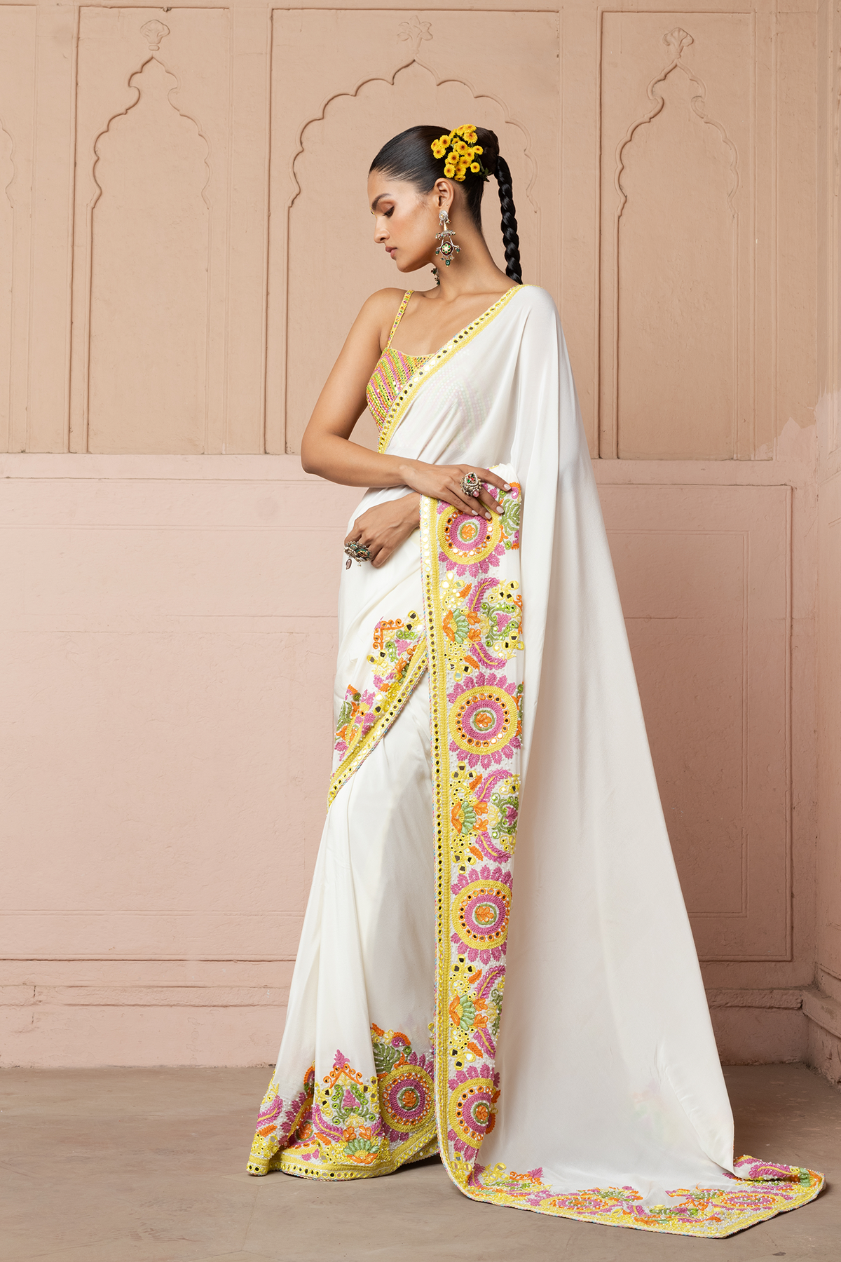 Multicolour mirror-embroidered blouse with an ivory saree featuring colourful cord embroidery.