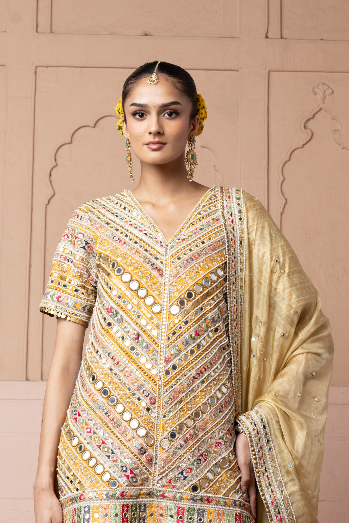 Mustard yellow embroidered kurta with mirror and threadwork detailing, paired with a coordinating flared sharara and gold dupatta.