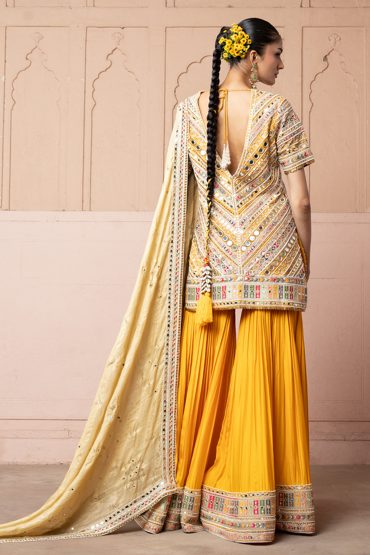 Mustard yellow embroidered kurta with mirror and threadwork detailing, paired with a coordinating flared sharara and gold dupatta.