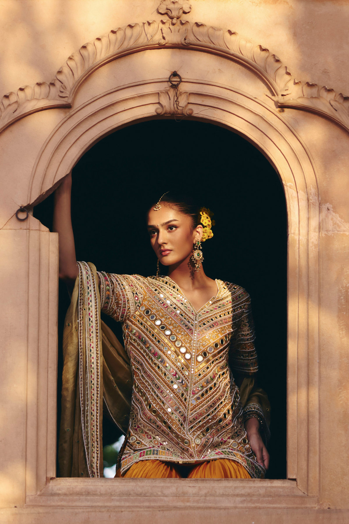 Mustard yellow embroidered kurta with mirror and threadwork detailing, paired with a coordinating flared sharara and gold dupatta.
