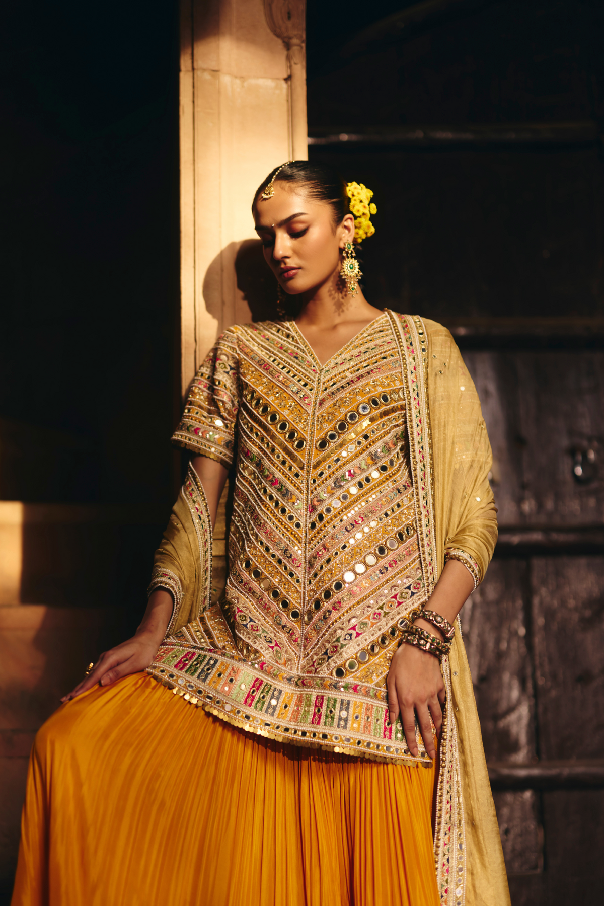 Mustard yellow embroidered kurta with mirror and threadwork detailing, paired with a coordinating flared sharara and gold dupatta.