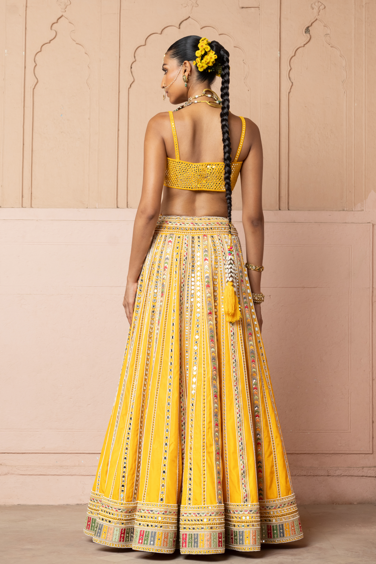 Mustard yellow lehenga adorned with multicolour mirror embroidery, paired with a matching embroidered blouse and sheer embellished dupatta.