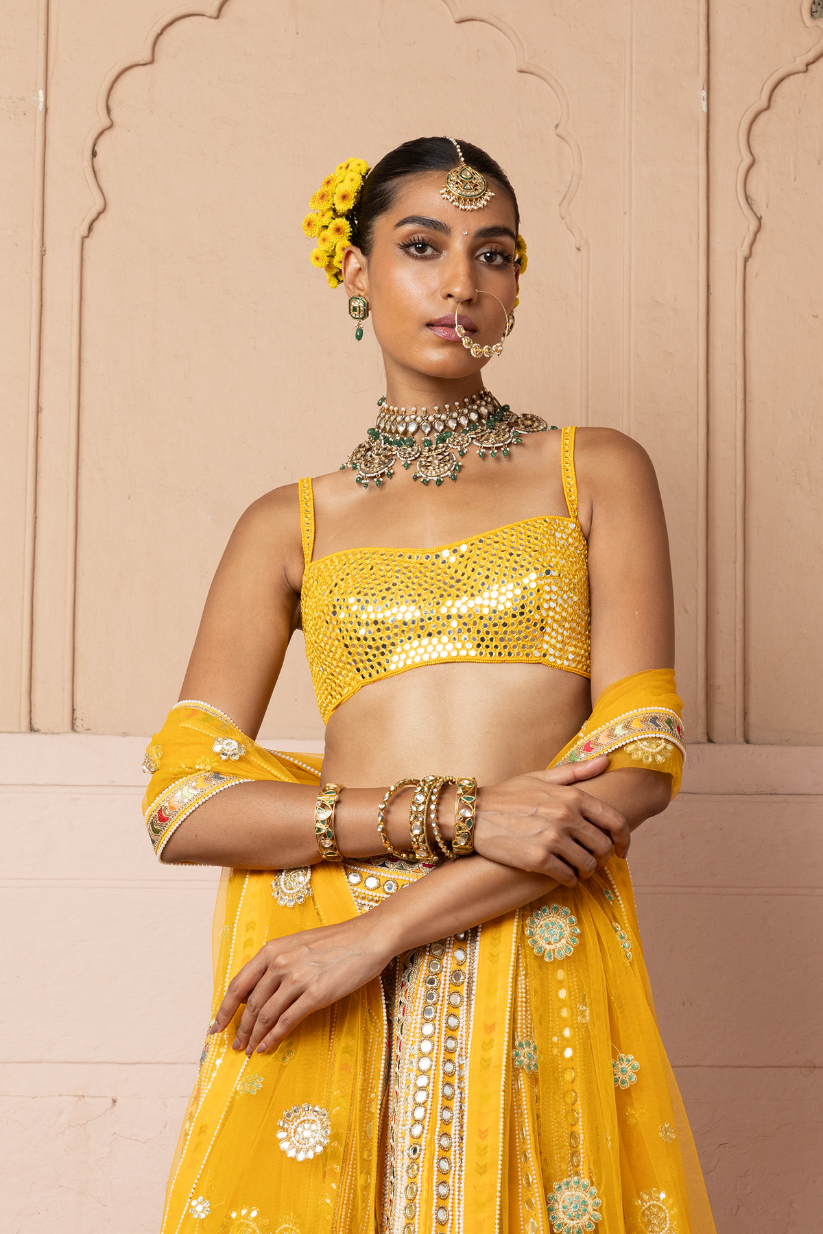 Mustard yellow lehenga adorned with multicolour mirror embroidery, paired with a matching embroidered blouse and sheer embellished dupatta.