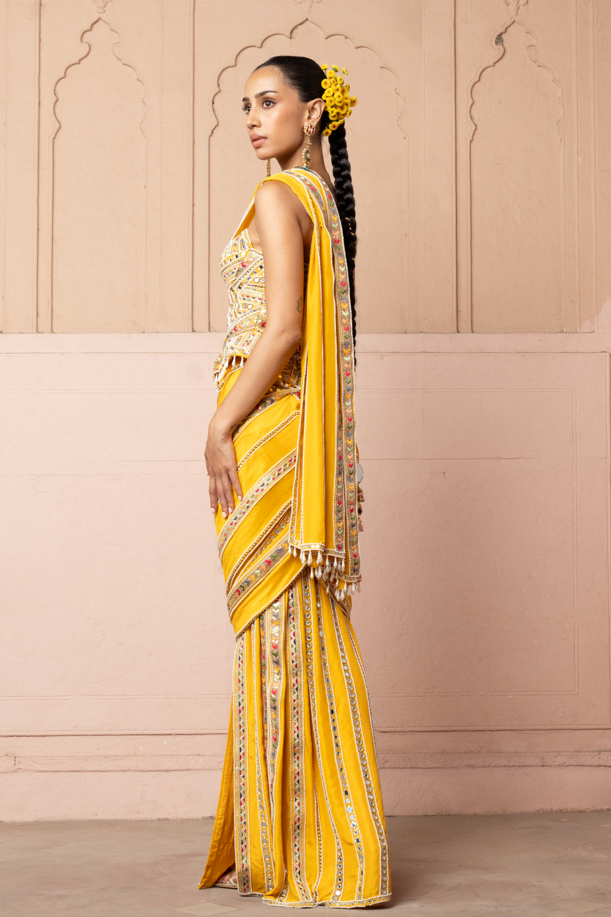 Mustard yellow pre-draped saree, paired with a heavily embroidered corset blouse with mirror and sequin embellishments.