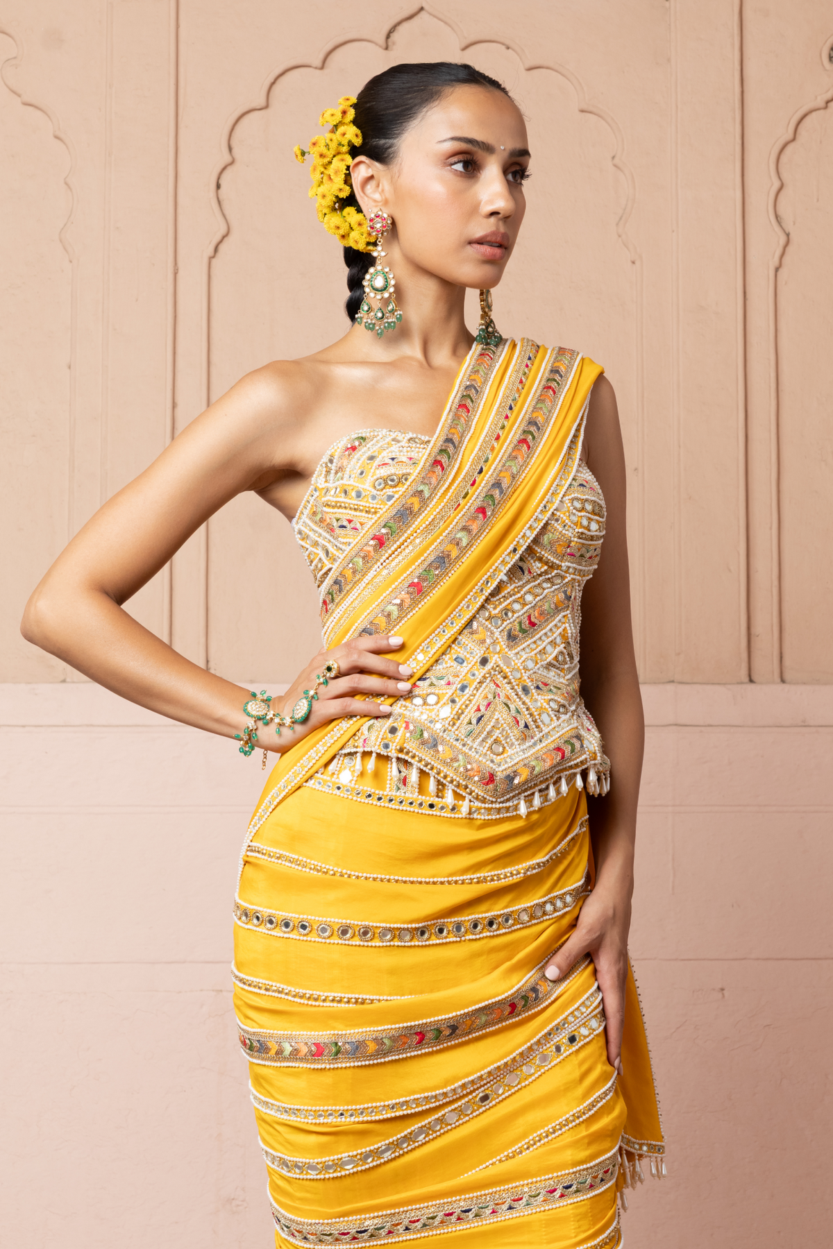 Mustard yellow pre-draped saree, paired with a heavily embroidered corset blouse with mirror and sequin embellishments.
