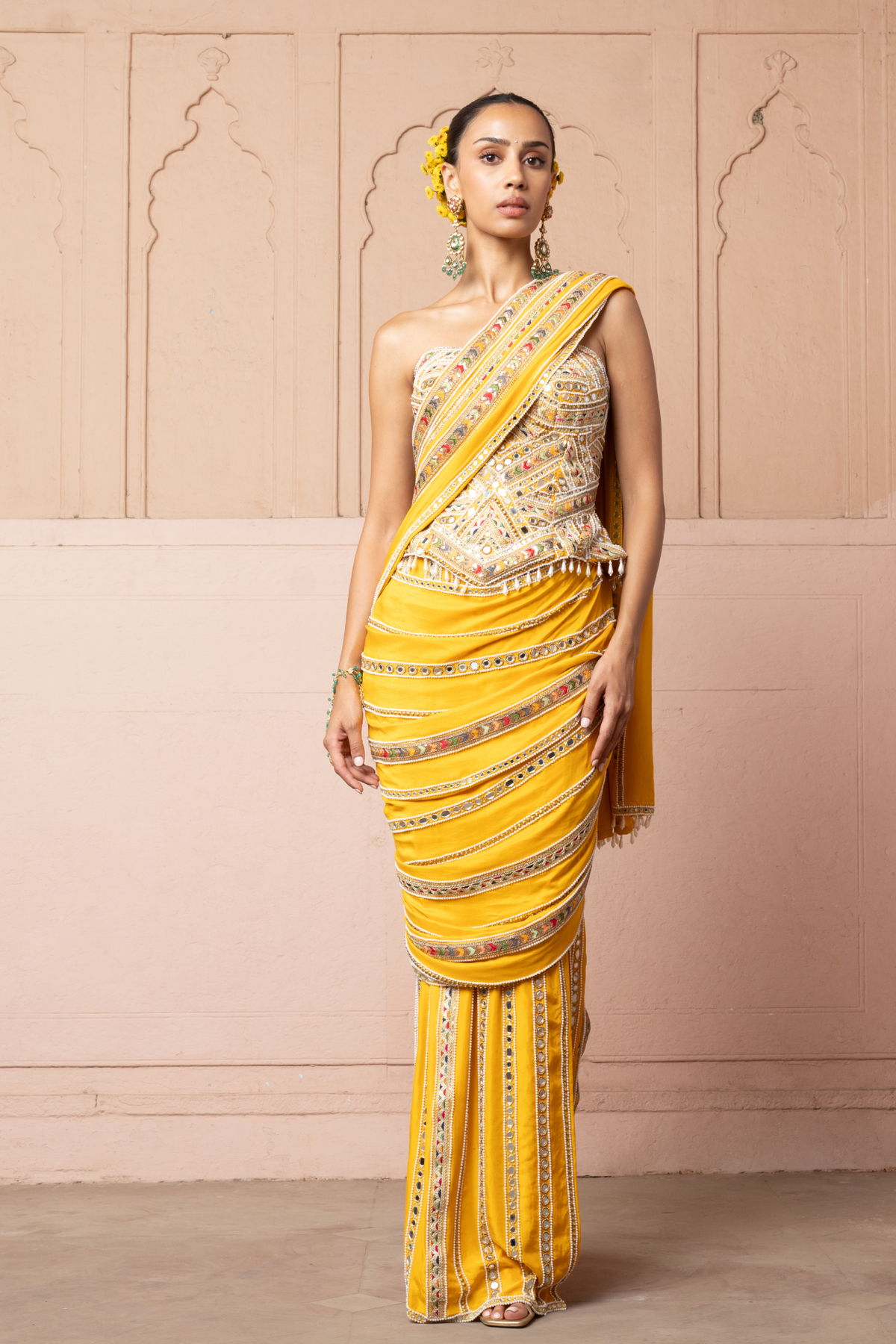 Mustard yellow pre-draped saree, paired with a heavily embroidered corset blouse with mirror and sequin embellishments.