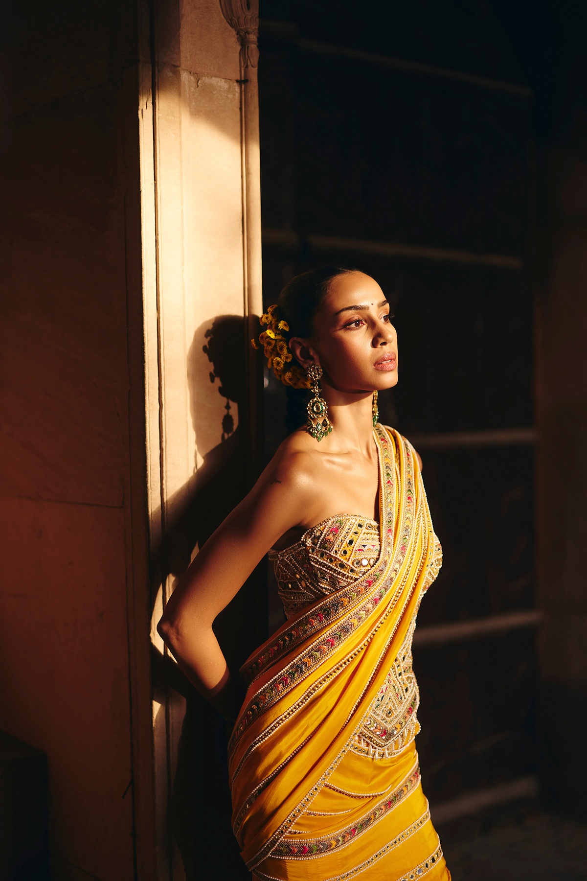 Mustard yellow pre-draped saree, paired with a heavily embroidered corset blouse with mirror and sequin embellishments.